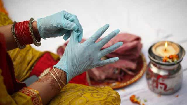 A woman wearing surgical gloves performs Karwa Chauth rituals in New Delhi on November 4. Cases in India have been dipping since hitting a peak of nearly 100,000 a day in September, but experts have sounded alarm over a potential spike due to increased movement during the festive season centred on Diwali.