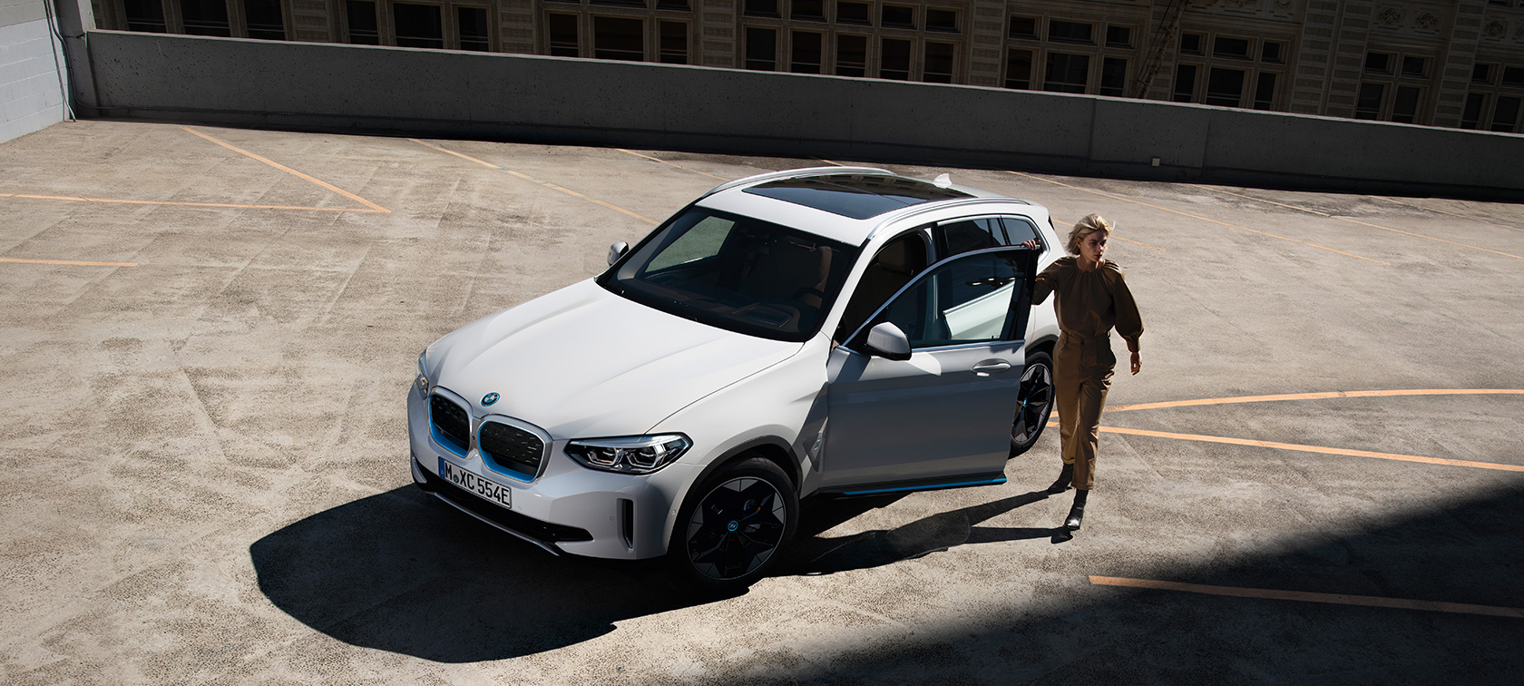 BMW iX3 G08 2020 Mineral White metallizzato vista anteriore a tre quarti con donna su sfondo urbano