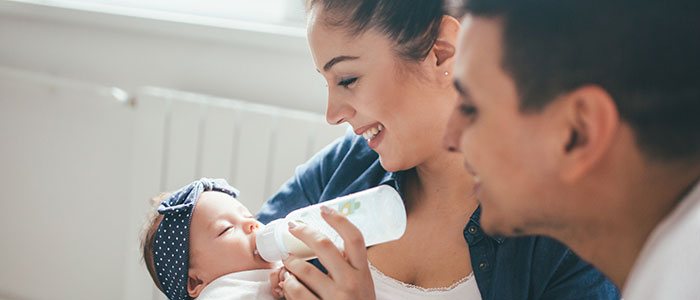 parents feeding an infant with a bottle